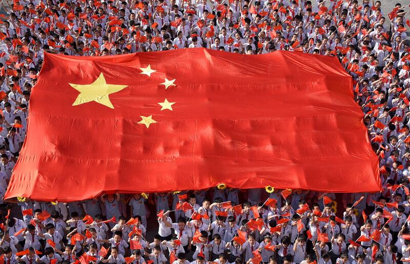 2019 年 9 月 1 日,在中国河北省邯郸市新学期开始的活动中,小学生举着一面巨大的中国国旗演奏一首名为“我和我的国家”的歌曲。(路透社)